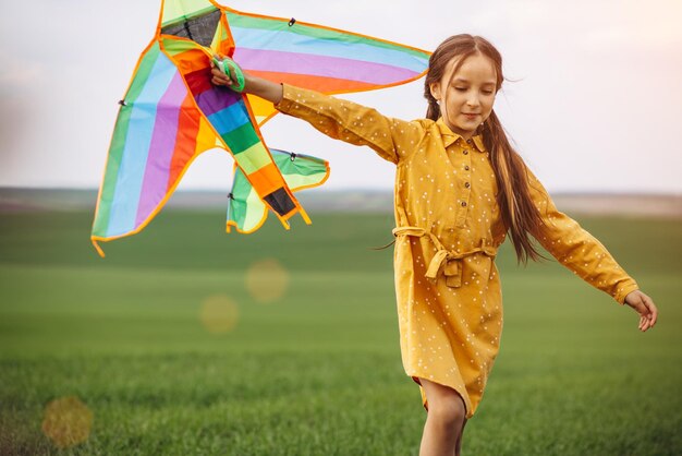 Niña jugando con cometas de colores en el campo verde