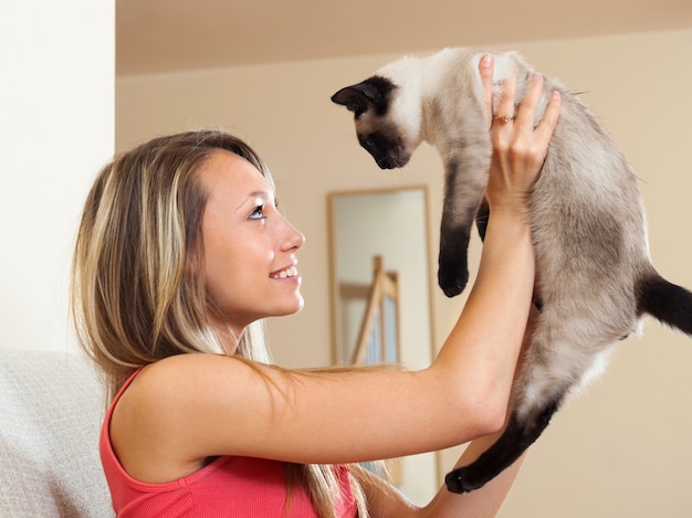 Niña jugando con gatito siamés