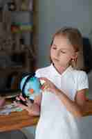 Foto gratuita niña jugando con un globo terráqueo