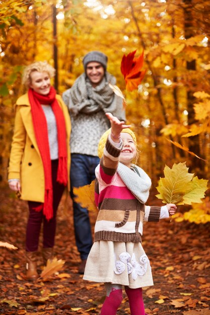 Niña jugando con hojas de otoño