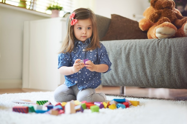 Niña jugando con juguetes en la sala de estar