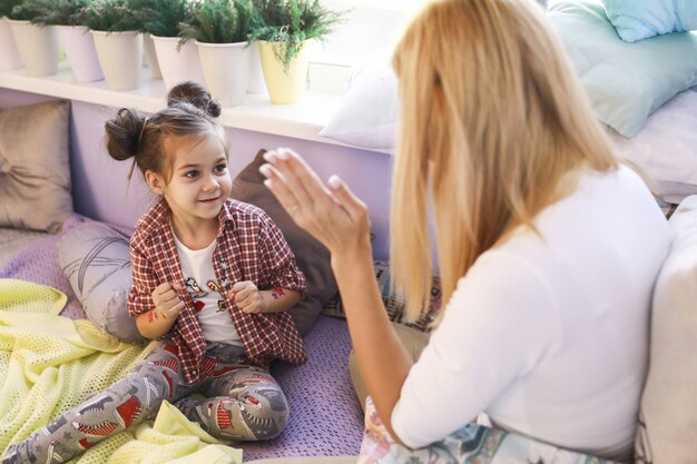 Niña jugando con la madre cerca de la ventana