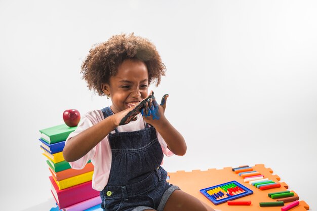 Niña jugando con las manos de color con pintura en el estudio