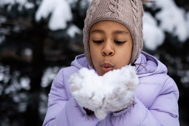 Niña jugando con nieve afuera en un día de invierno