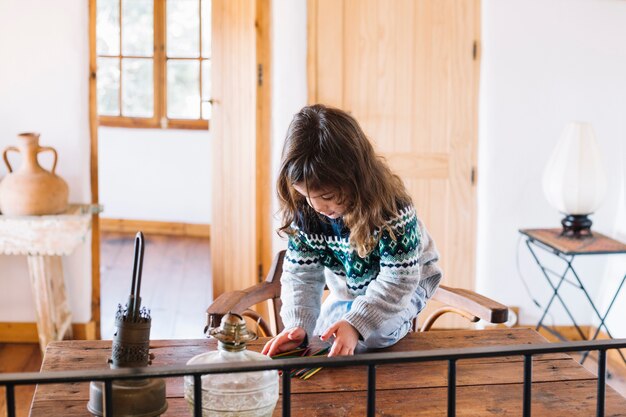 Niña jugando con palos de plástico en el escritorio de madera