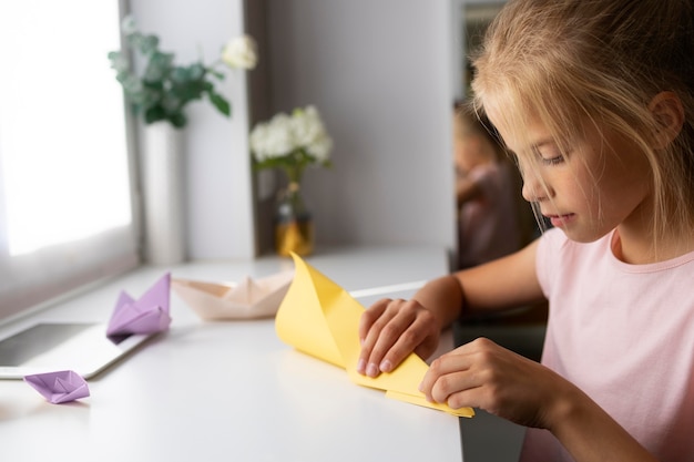 Niña jugando con papel de origami en casa