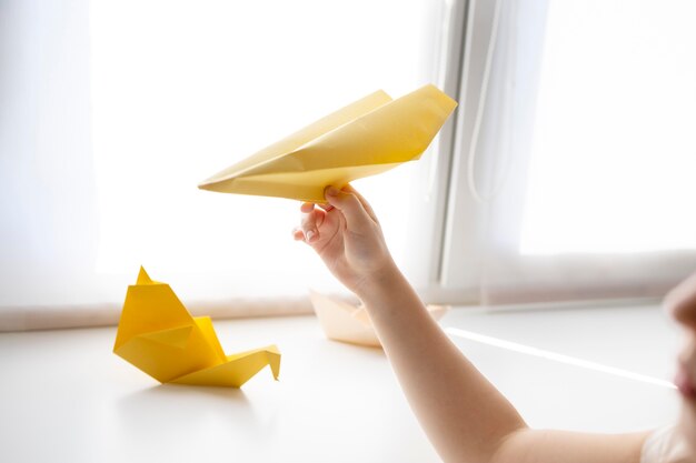 Niña jugando con papel de origami en casa