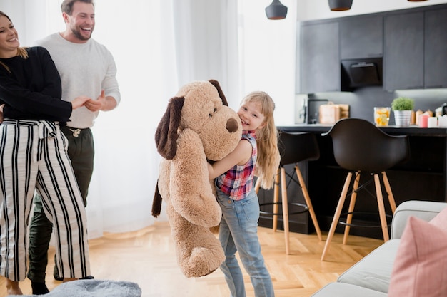 Niña jugando con peluche cerca de los padres