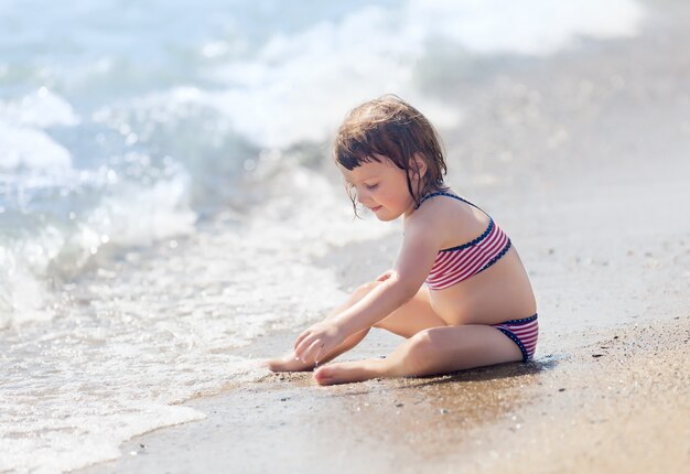 niña jugando en la playa de arena