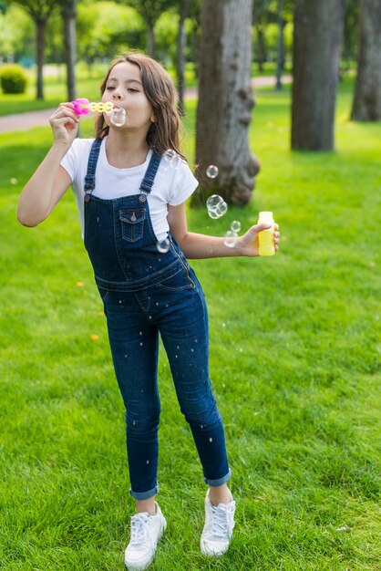 Niña jugando con pompas de jabón al aire libre