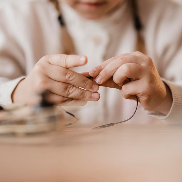 Niña jugando con primer plano de cables eléctricos