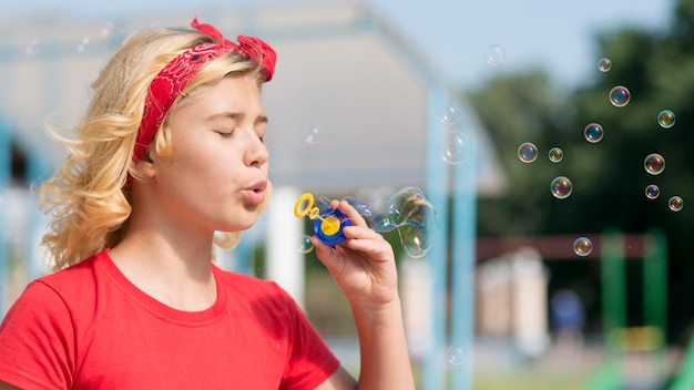 Foto gratuita niña jugando con soplador de burbujas al aire libre