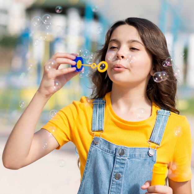 Niña jugando con soplador de burbujas