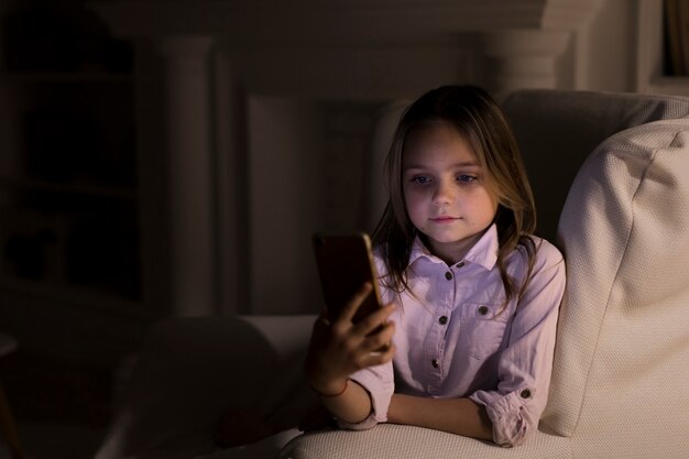 Niña jugando en su teléfono a casa