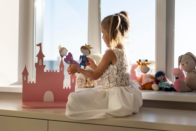 Niña jugando con títeres en casa