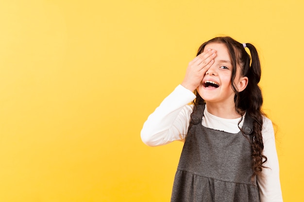 Foto gratuita niña juguetona que cubre los ojos con la mano