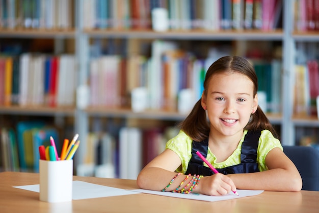 Foto gratuita niña con lápiz rosa en la biblioteca