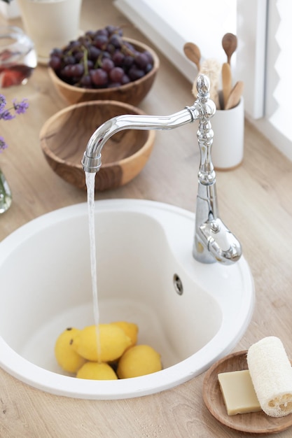 La niña lava limones en la cocina Haciendo una bebida refrescante de verano Concepto de comida saludable