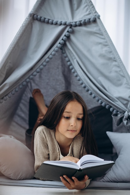 Foto gratuita niña leyendo libro acostado en vigvam