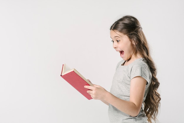 Foto gratuita niña leyendo un libro con emoción