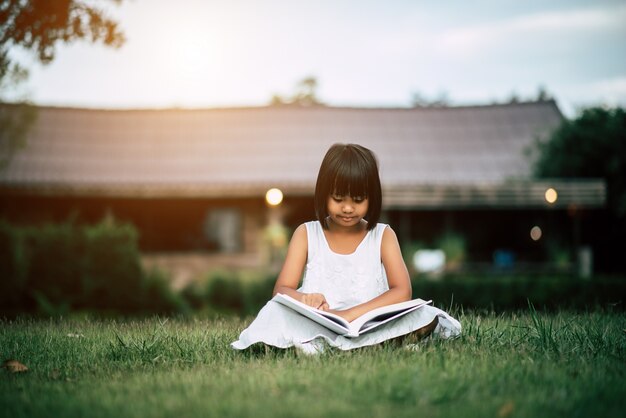 Niña leyendo un libro en el jardín de la casa