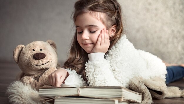 Niña leyendo un libro con un oso de peluche en el suelo, concepto de relajación y amistad