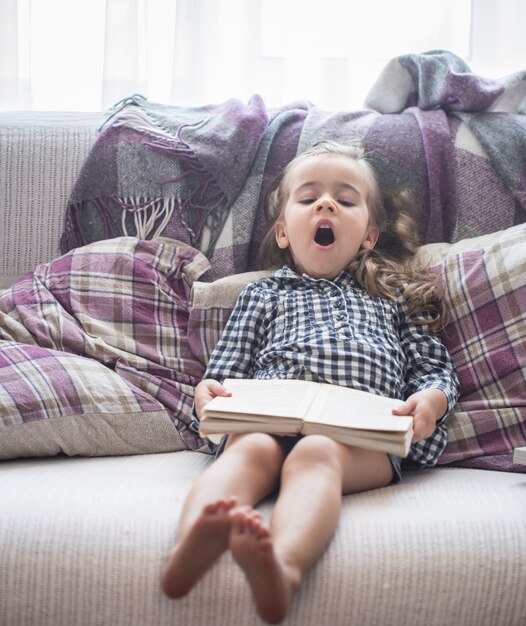 Niña leyendo un libro en el sofá