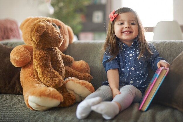 Niña leyendo un libro con sus osos de peluche