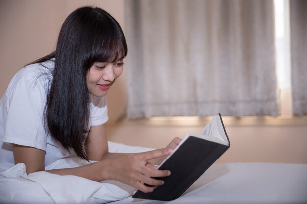 Niña leyendo un libro y tomando café en la cama por la mañana