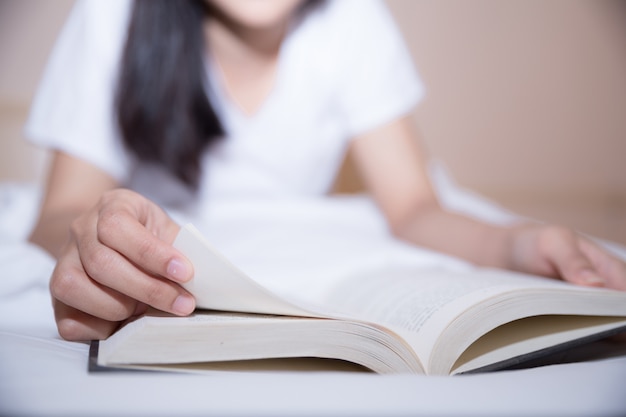 Niña leyendo un libro y tomando café en la cama por la mañana