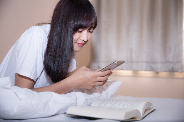 Niña leyendo un libro y tomando café en la cama por la mañana