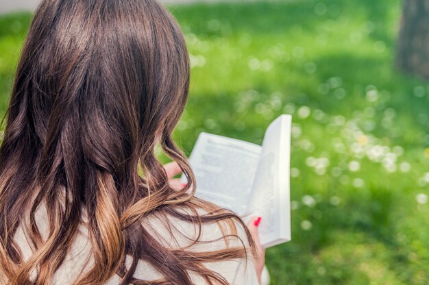 Niña con libro en el jardín verde. Mujer feliz libre. El conocimiento es poder. Sed de conocimiento. Libro en manos de mujer