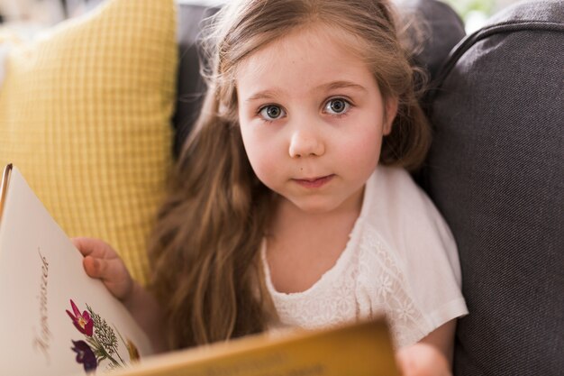 Niña con libro en sofá