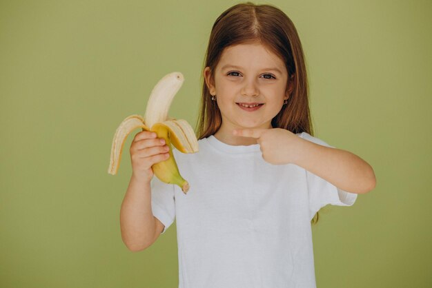 Niña linda aislada con plátano