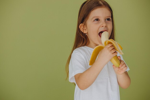 Niña linda aislada con plátano