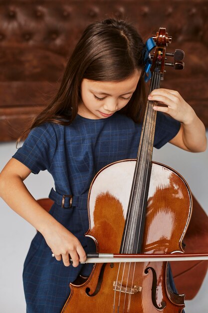 Niña linda aprendiendo a tocar el violonchelo