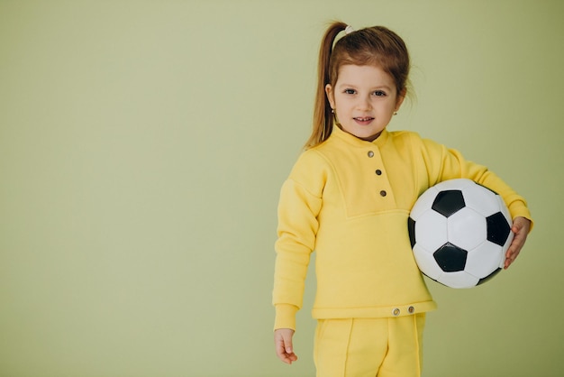 Niña linda con balón de fútbol en estudio