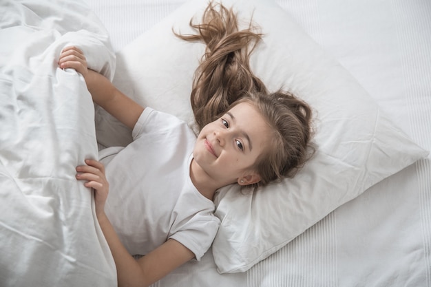 Niña linda en la cama se despertó por la mañana