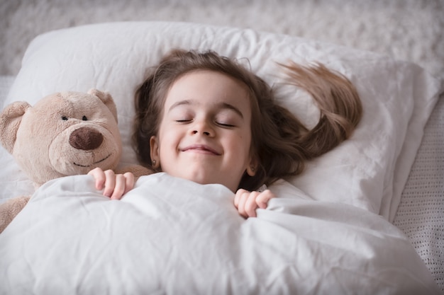 Niña linda en la cama con juguete