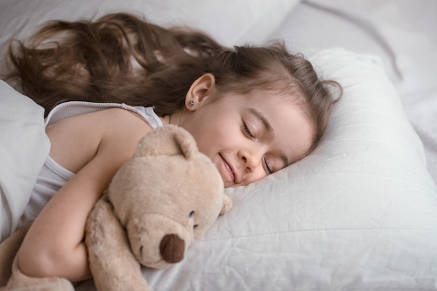 Niña linda en la cama con juguete