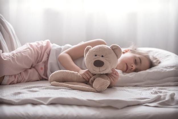 Niña linda en la cama con juguete