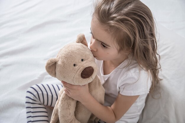 Niña linda en la cama con peluche