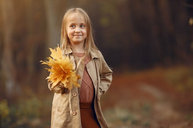 Niña linda camina en un parque de otoño