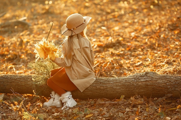 Niña linda camina en un parque de otoño