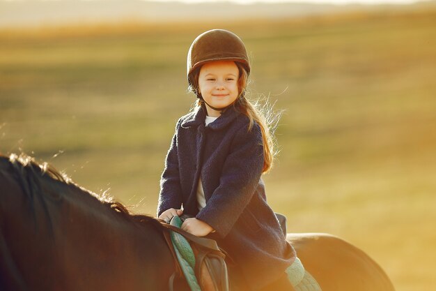 Niña linda en un campo de otoño con caballo