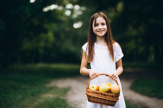 Niña linda con la cesta de fruta