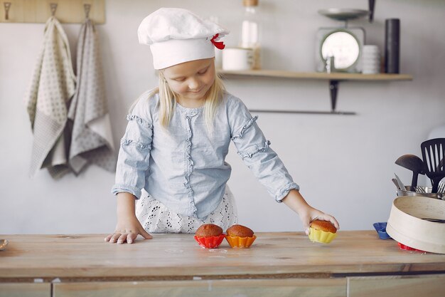 Niña linda en una cocina con cupcake