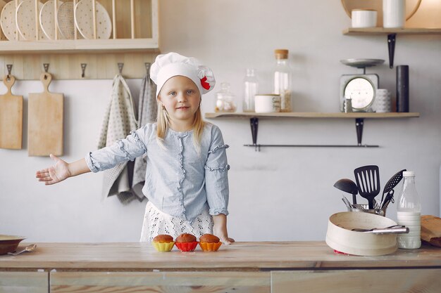 Niña linda en una cocina con cupcake