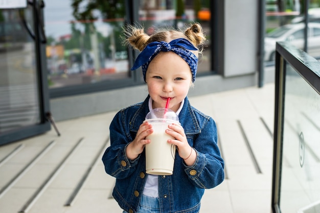 Niña linda con cóctel de leche en la calle