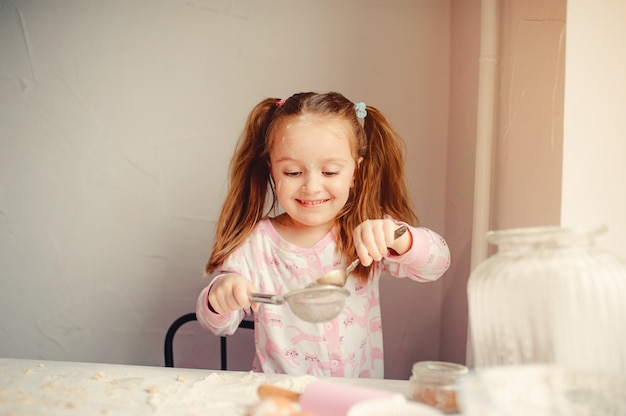 La niña linda se divierte en una cocina